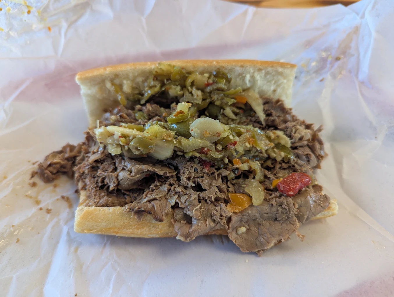 Italian beef sandwich dipped in au jus with hot peppers